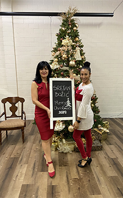 Two ladies posing with the Mary Christmas panel in the front of the Christams tree